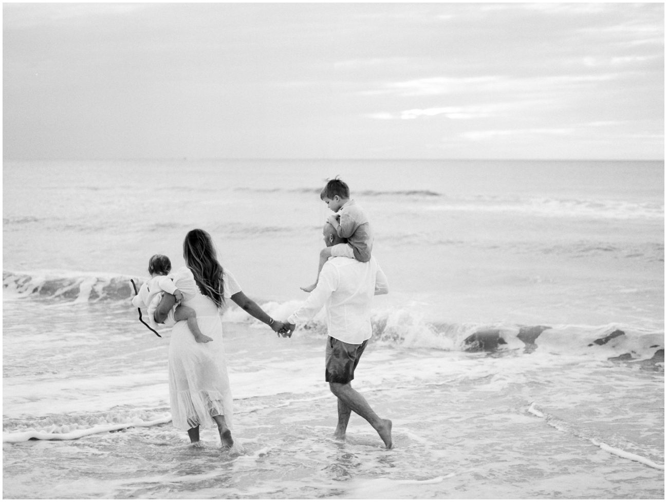 a family walking the coastline of the beach in Naples for their beach family session