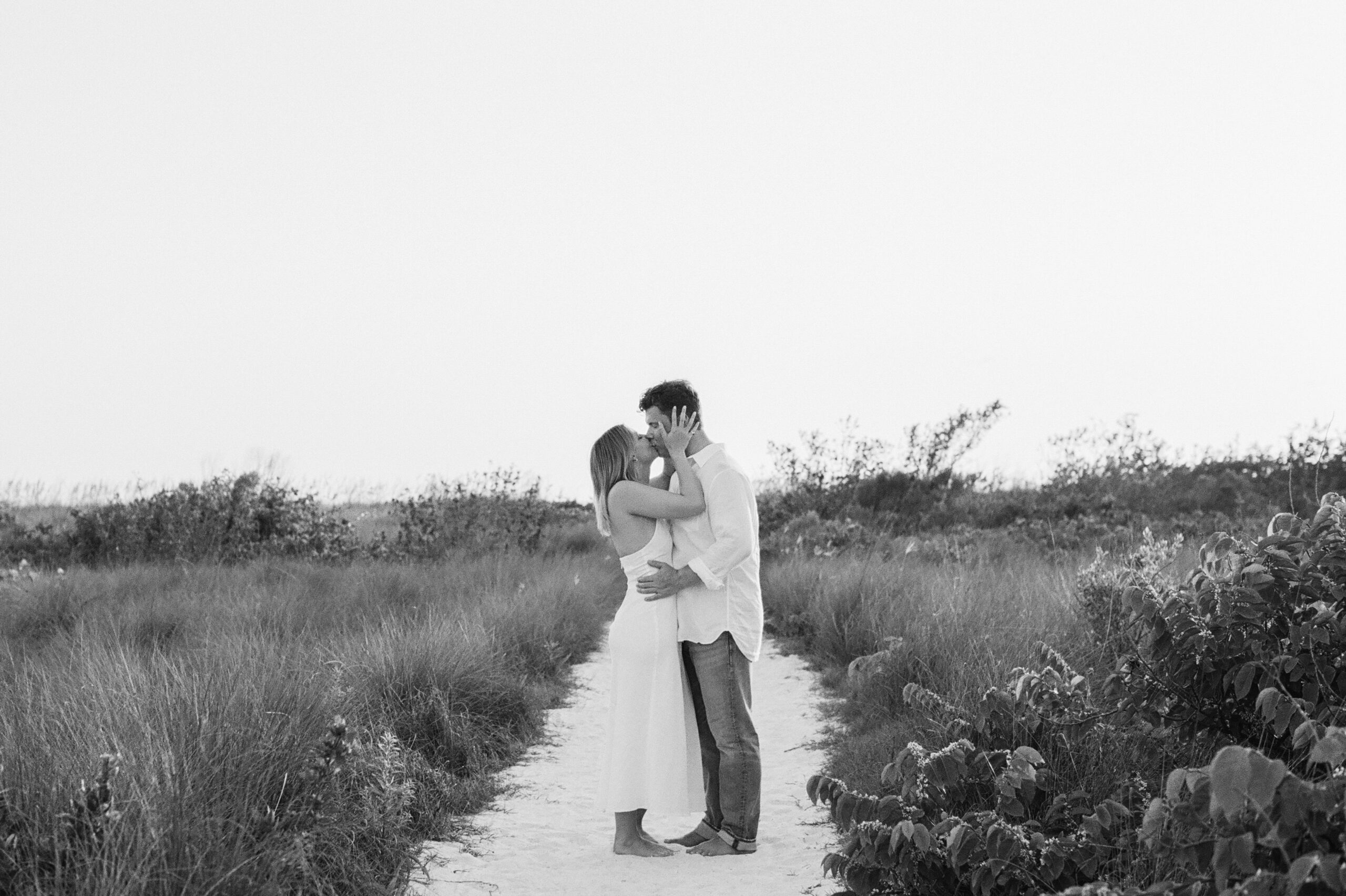 a black and white photo couple is kissing on a path in marco island after just getting engaged on the beach