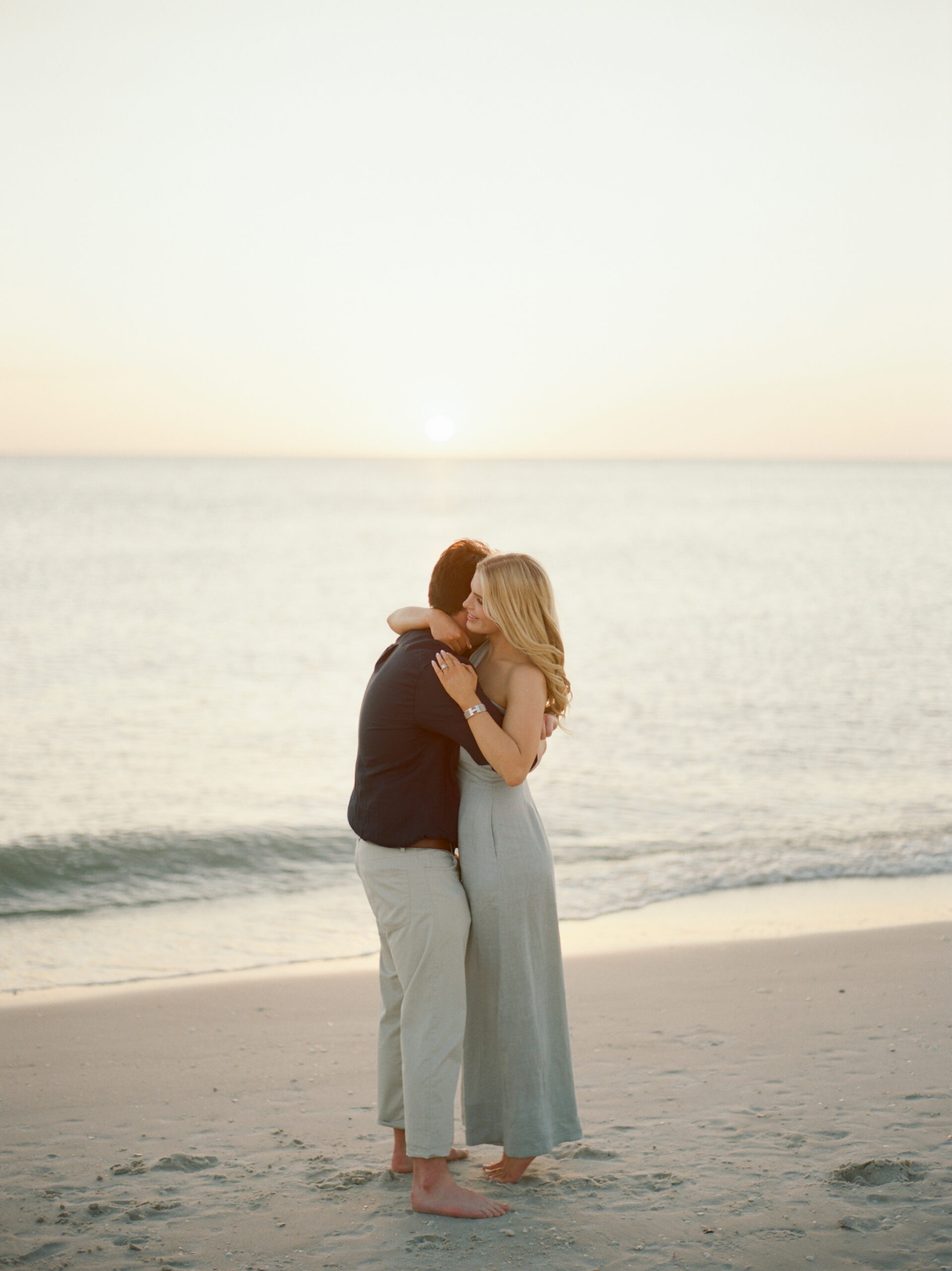 an engaged couple hugging during the sunset of beaches of Naples near the Four Seasons