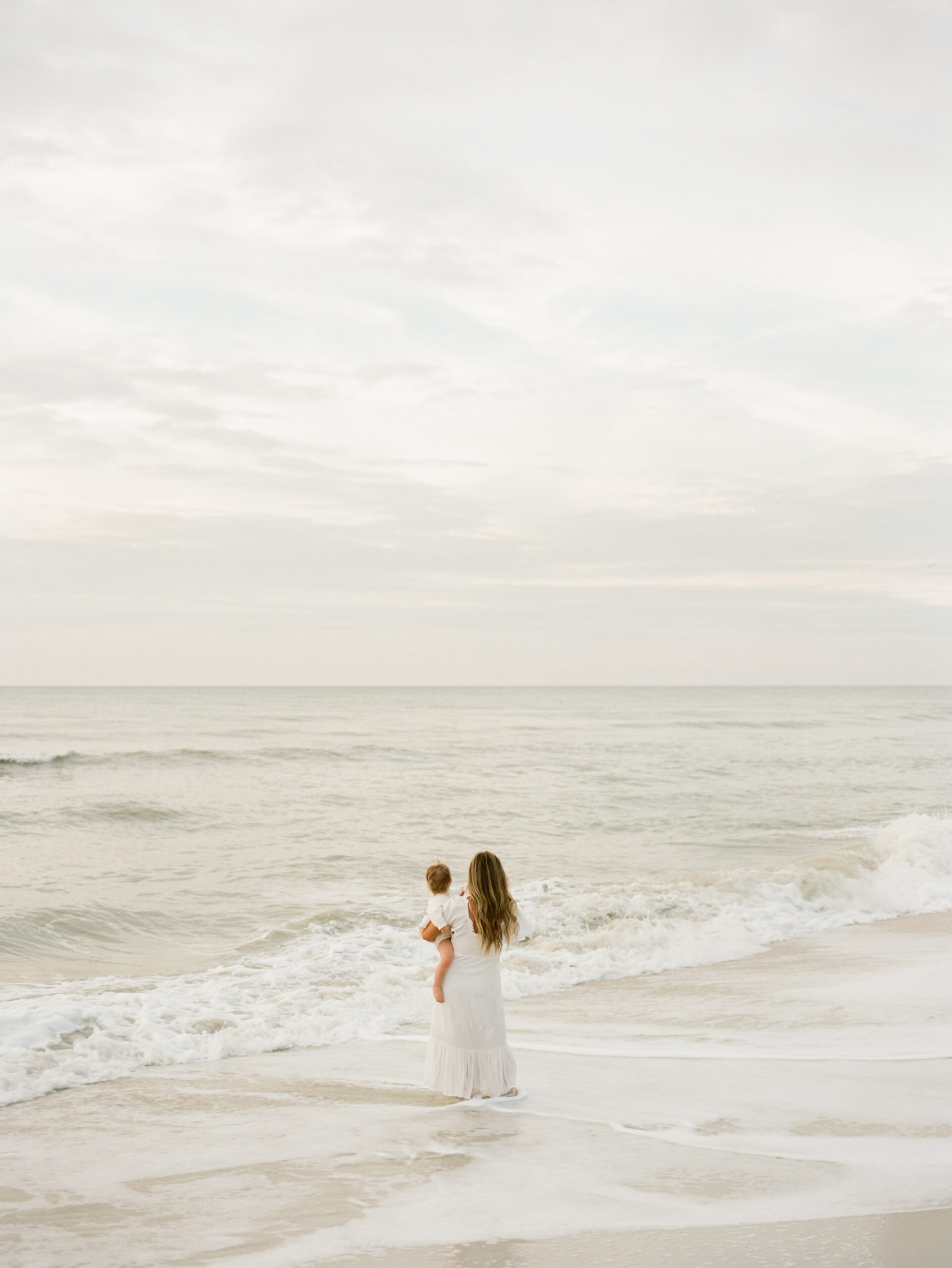 a mother holding her baby looking off at the ocean at the four seasons naples florida